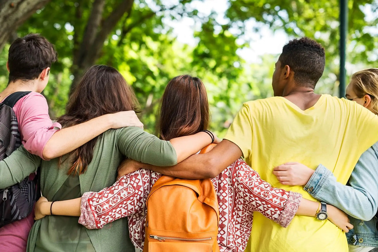 Jugendliche stehen da mit Rucksäcken von hinten